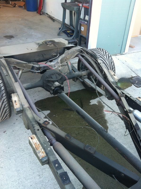 A car frame is sitting on the ground in a garage
