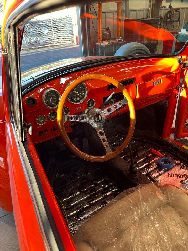 The inside of an orange car with a wooden steering wheel