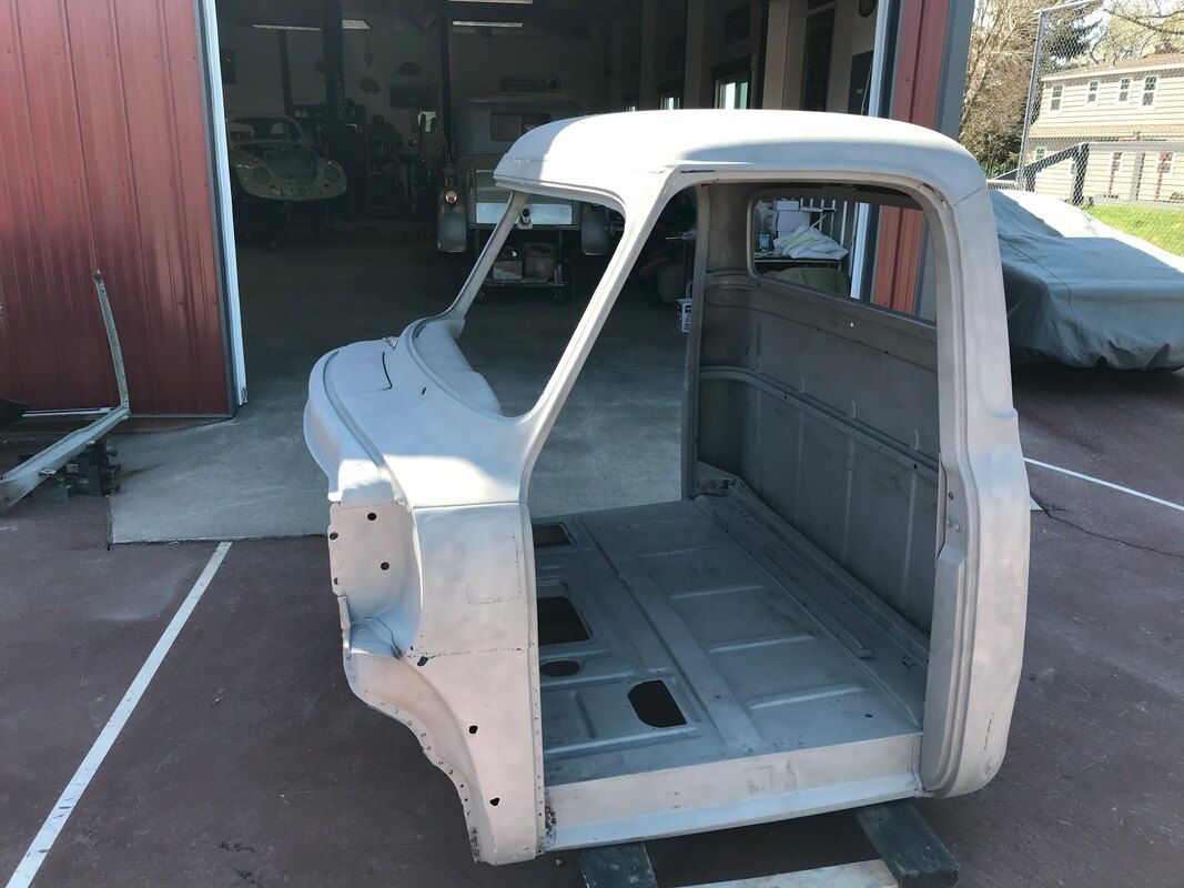 A truck body is sitting in front of a garage door.