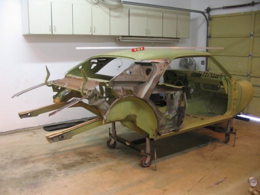 A green car is being built in a garage