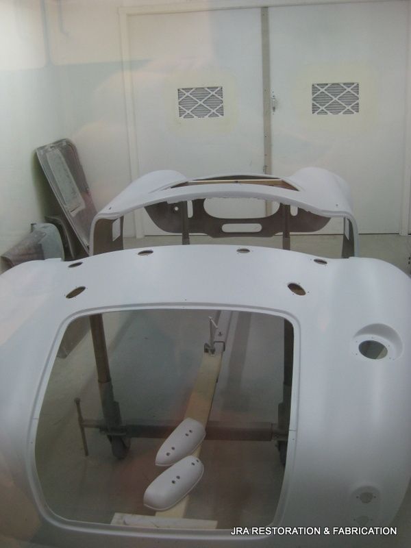 A white car is being painted in a garage