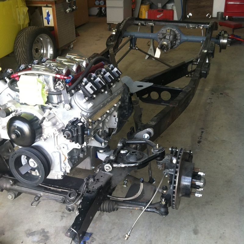 A car engine is sitting on a chassis in a garage