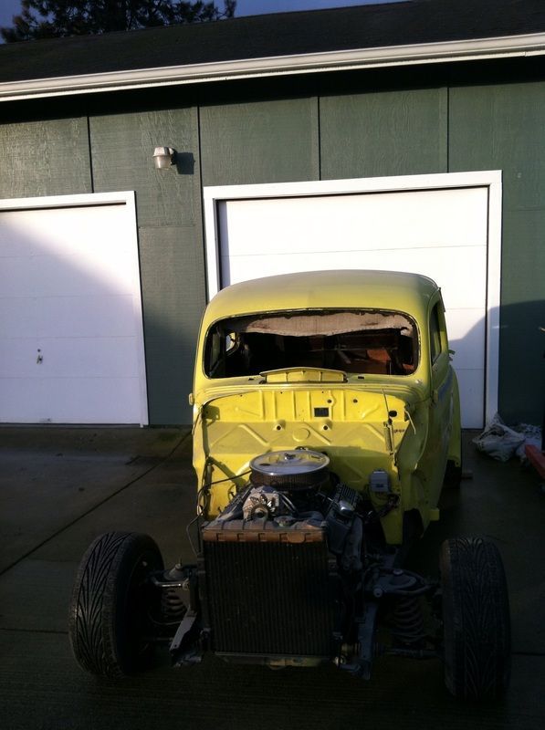 A yellow car is parked in front of a garage