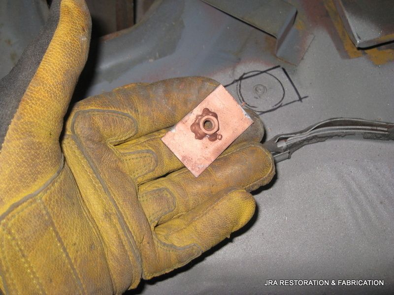 A person wearing yellow gloves is holding a piece of metal in their hand.