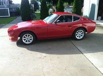 A red sports car is parked in a driveway next to a garage.