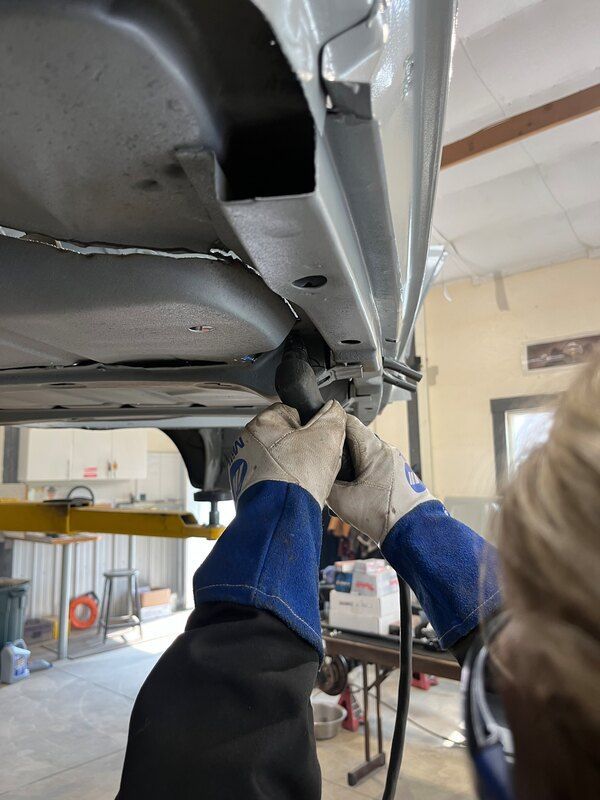 A person is working on the underside of a car