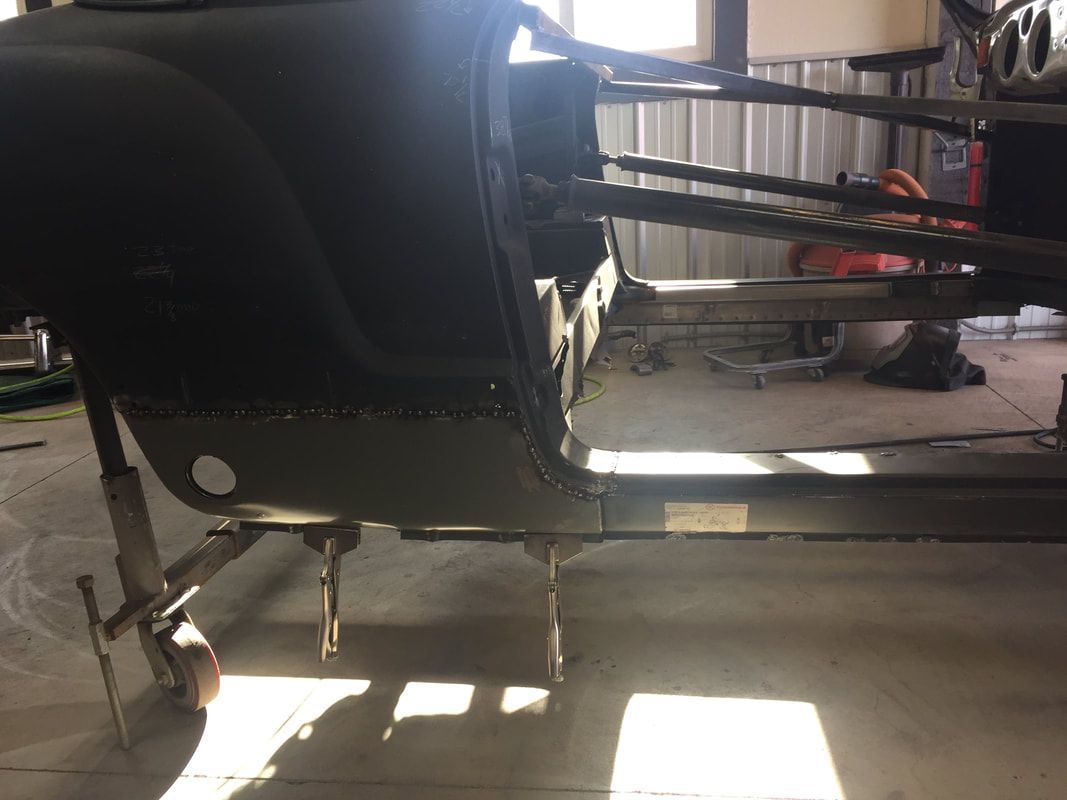 A black car is sitting on a cart in a garage.