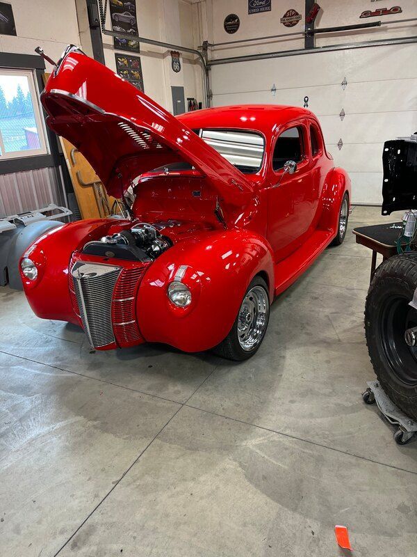 A red car with the hood up is parked in a garage