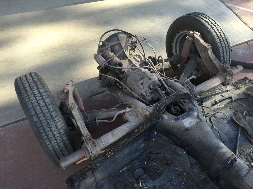 The chassis of a car is laying on the ground.
