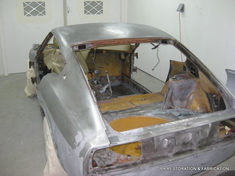 A silver car is sitting on a table in a garage.