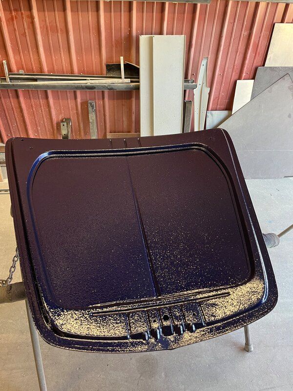 A purple trash can is sitting on a table in front of a red wall.