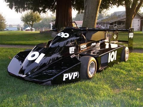 A black pvp race car is parked in the grass
