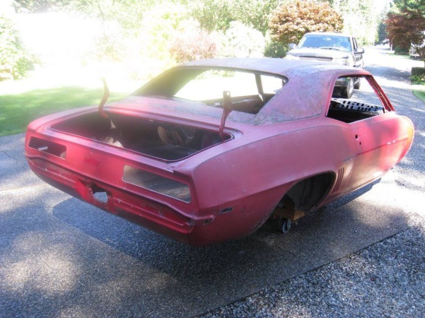 A red car with the trunk open is parked on the side of the road