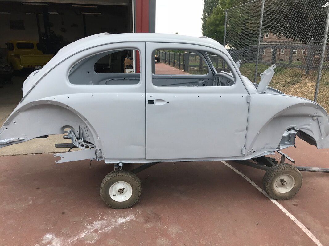 A white car is sitting on wheels in a parking lot.