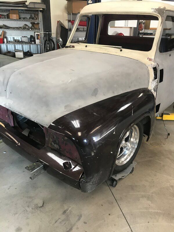 An old truck is sitting on a lift in a garage.