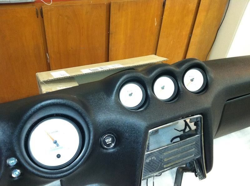 A black car dashboard with white gauges and buttons