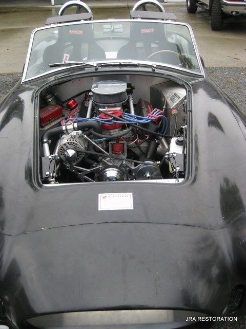 A black sports car with the hood open and the engine visible