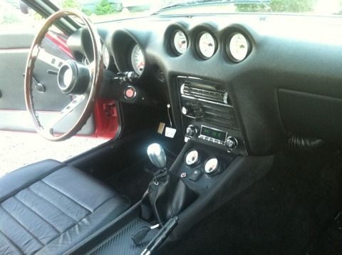 The interior of a red sports car with a wooden steering wheel