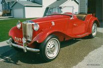A red sports car is parked in front of a garage.