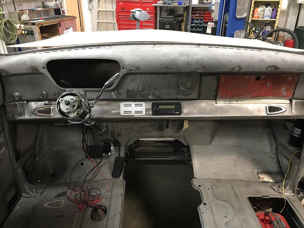 The dashboard of an old car is being restored in a garage.