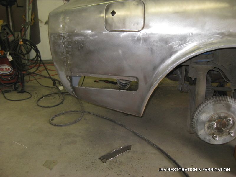 A silver car is being restored in a garage.