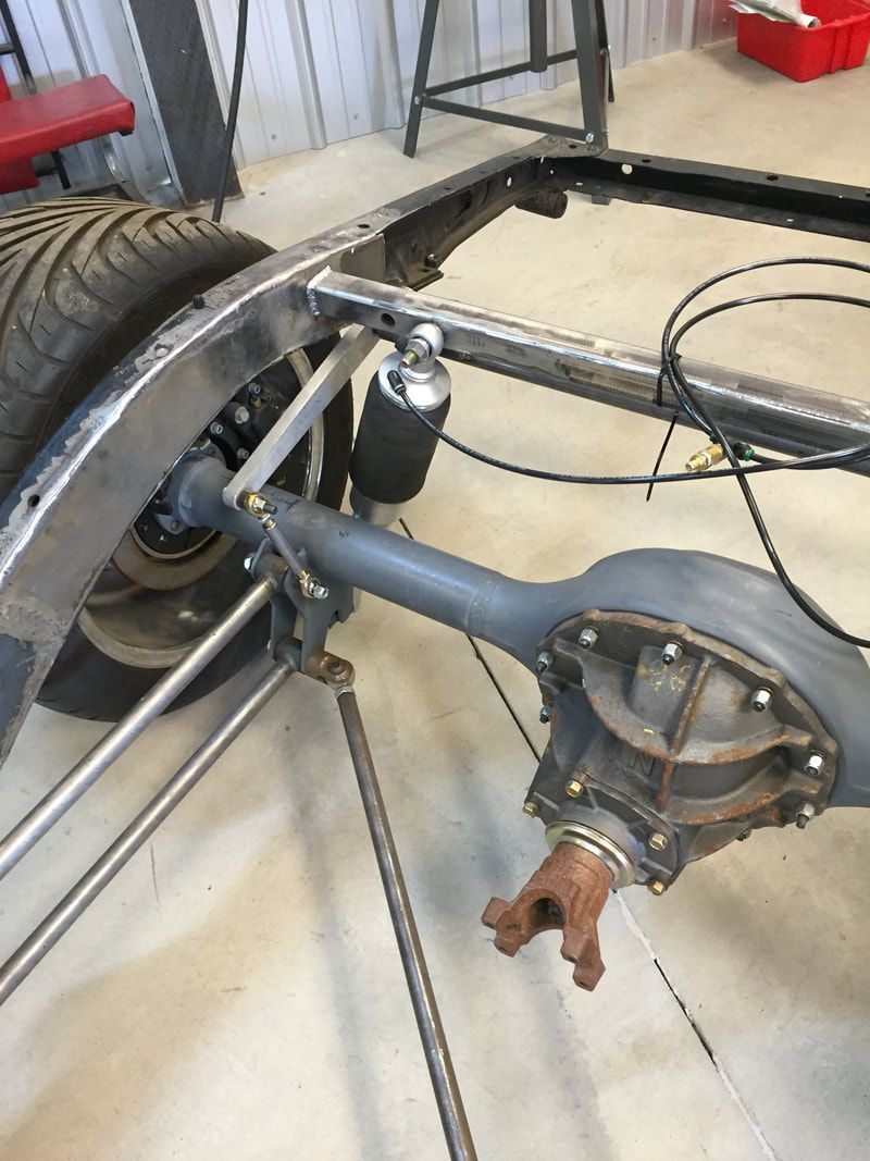 The rear end of a car is being built in a garage.