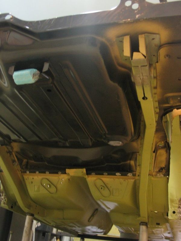 The underside of a car is shown in a garage