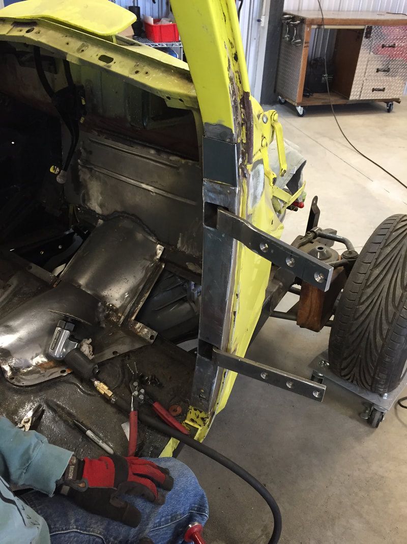 A person is working on a yellow car in a garage.