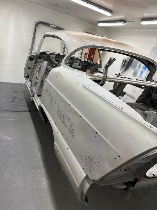 A 1958 Buick Roadmaster  is sitting in a garage with the door open.