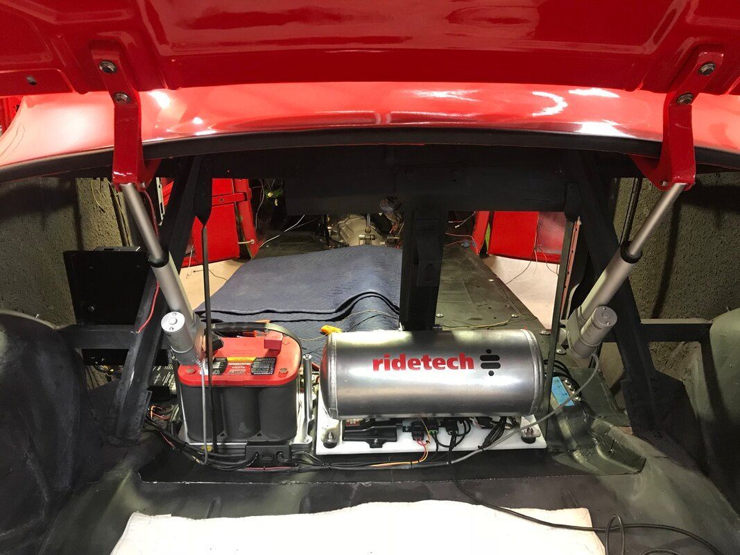 The trunk of a red car with a air suspension system in it