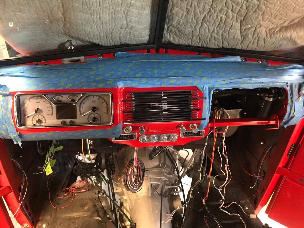 The dashboard of a red car is covered in blue tape.