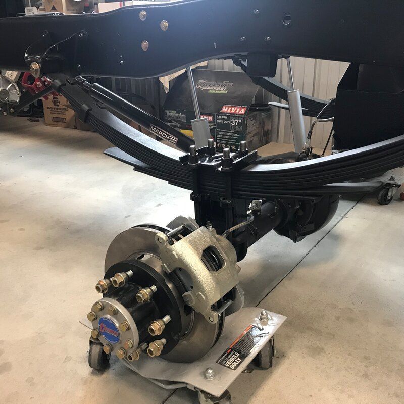 A rear end of a truck is sitting on a cart in a garage