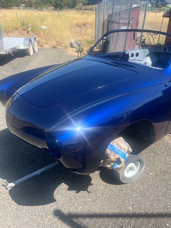 A blue car is parked on the side of the road next to a trailer.