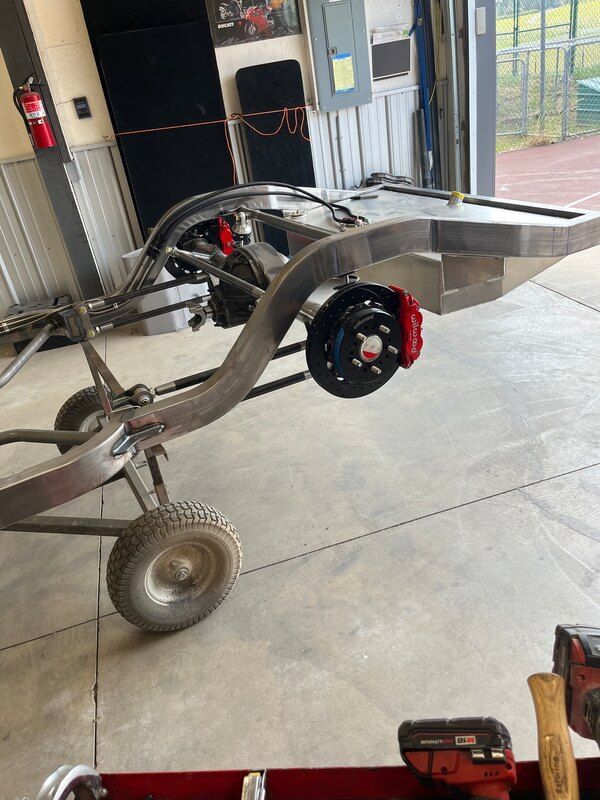 A chassis is sitting on a cart in a garage.