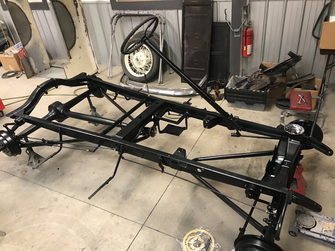 A car frame is sitting on the floor in a garage.