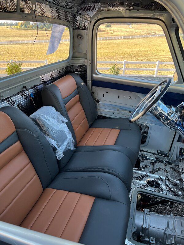The inside of a truck with black and brown seats and a steering wheel.