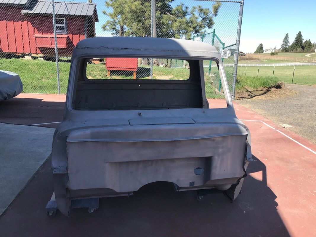 A truck is sitting in a parking lot with a red barn in the background.