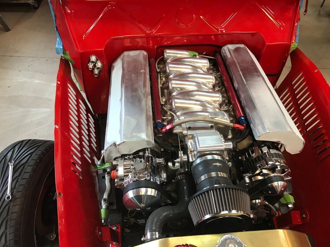 A close up of a red car engine with the hood open