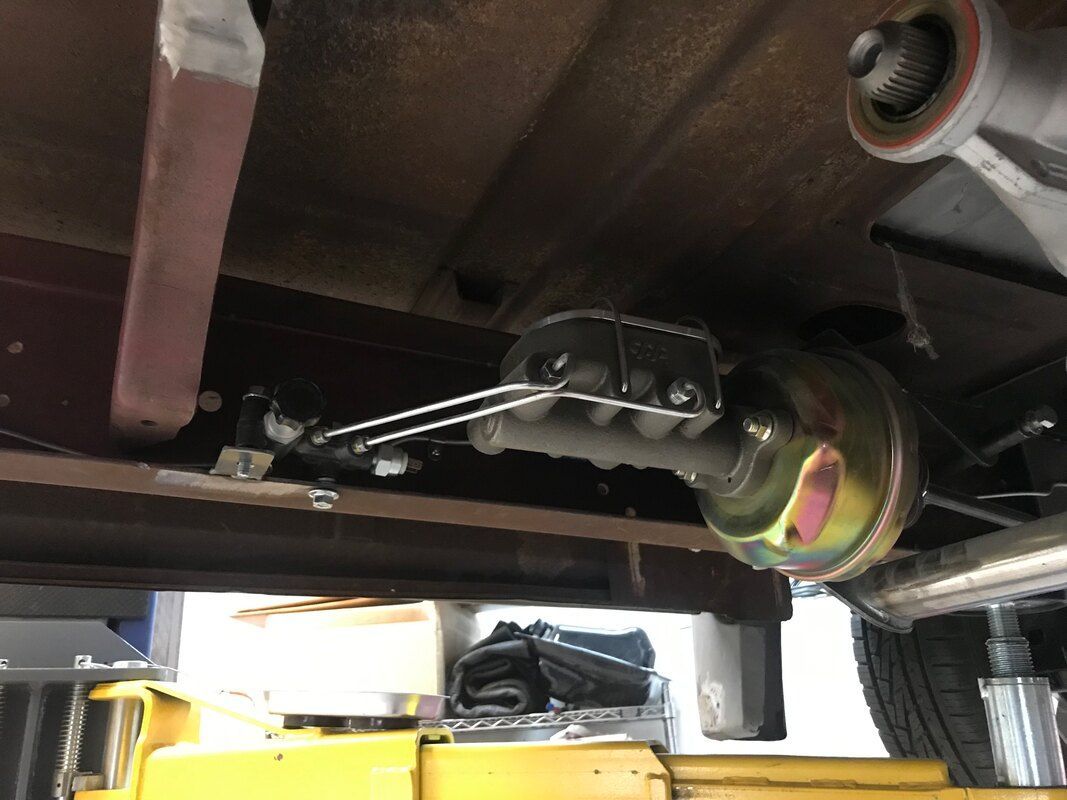 The underside of a car is shown with a yellow jack in the foreground