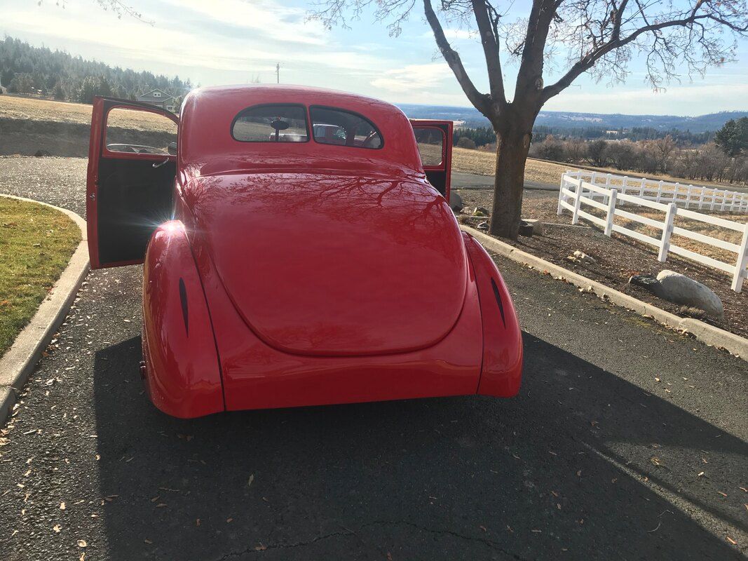 A red car is parked on the side of the road with its doors open.