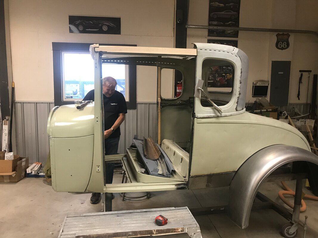 A man is standing in front of a truck in a garage.