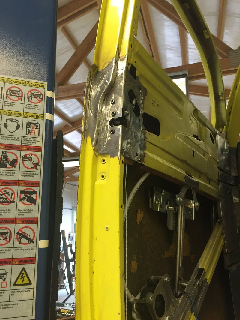 A yellow car door is being repaired in a garage