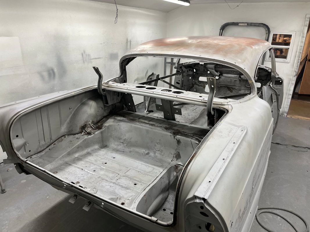 A 1958 Buick Roadmaster  is sitting in a garage with the trunk open.