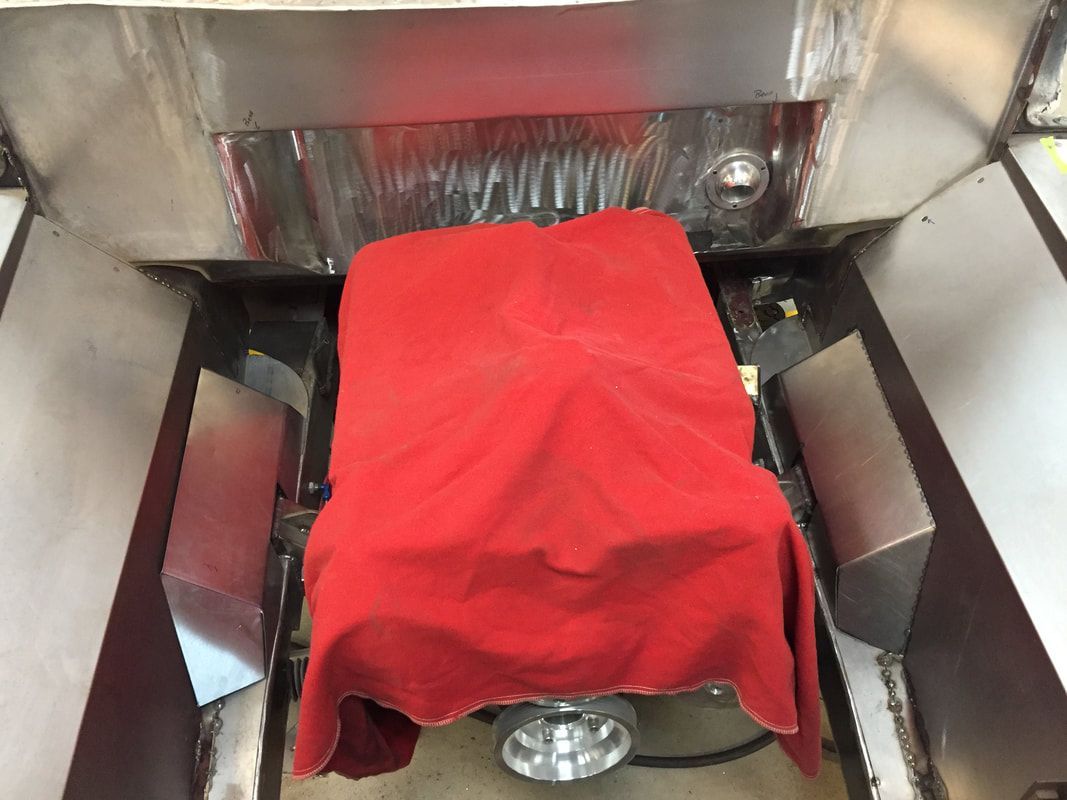 A red cloth is covering a wheelchair in a garage.