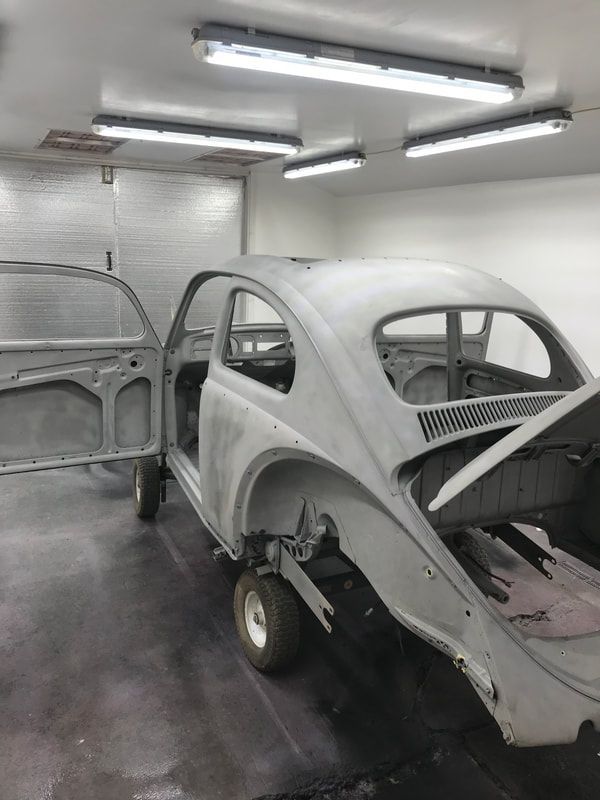 A car is sitting in a garage with its doors open.