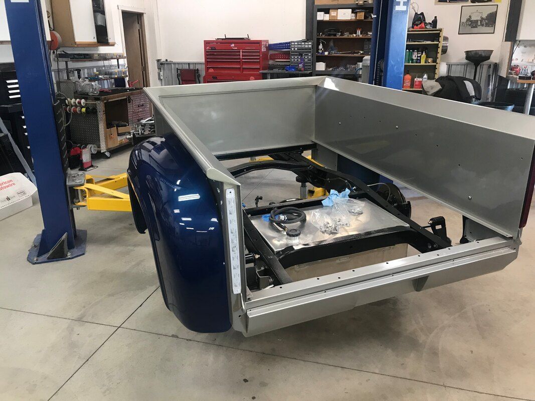 A blue truck with a trailer attached to it in a garage.