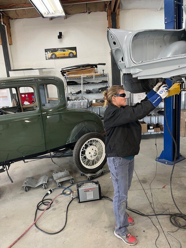 A woman is working on a car in a garage.