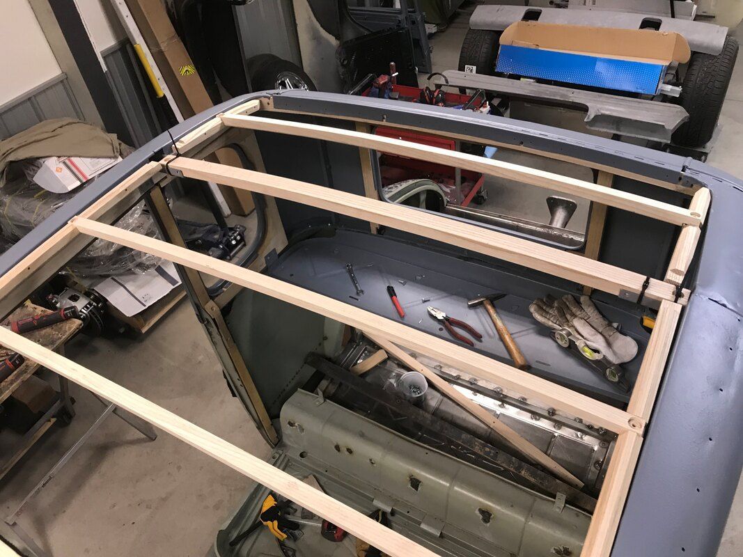 A wooden frame is being built on top of a car in a garage.