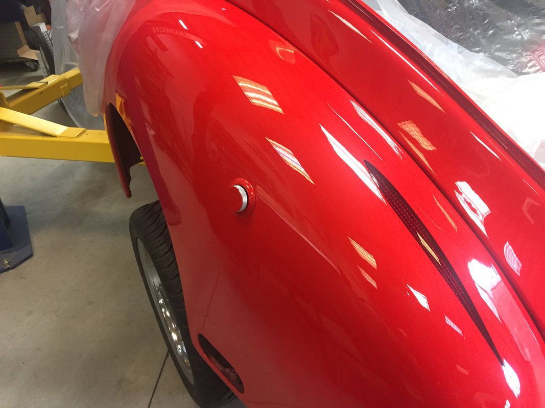 A red car is sitting on a yellow lift in a garage