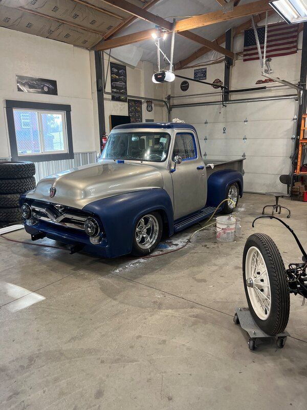 A truck is parked in a garage next to a tire.